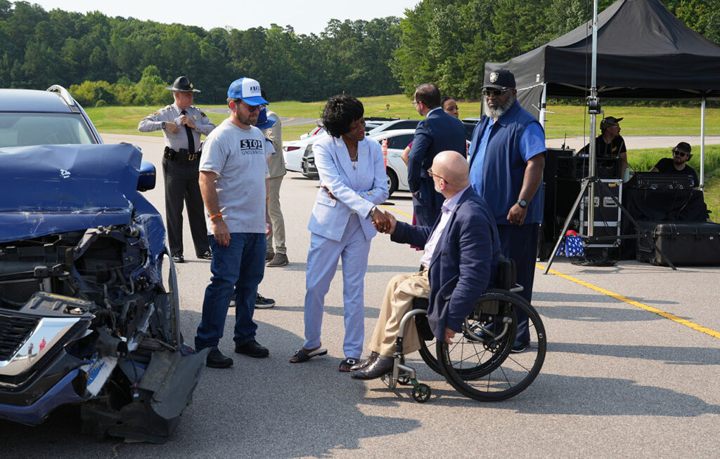 Guests and safety professionals gathered around a crash-test vehicle