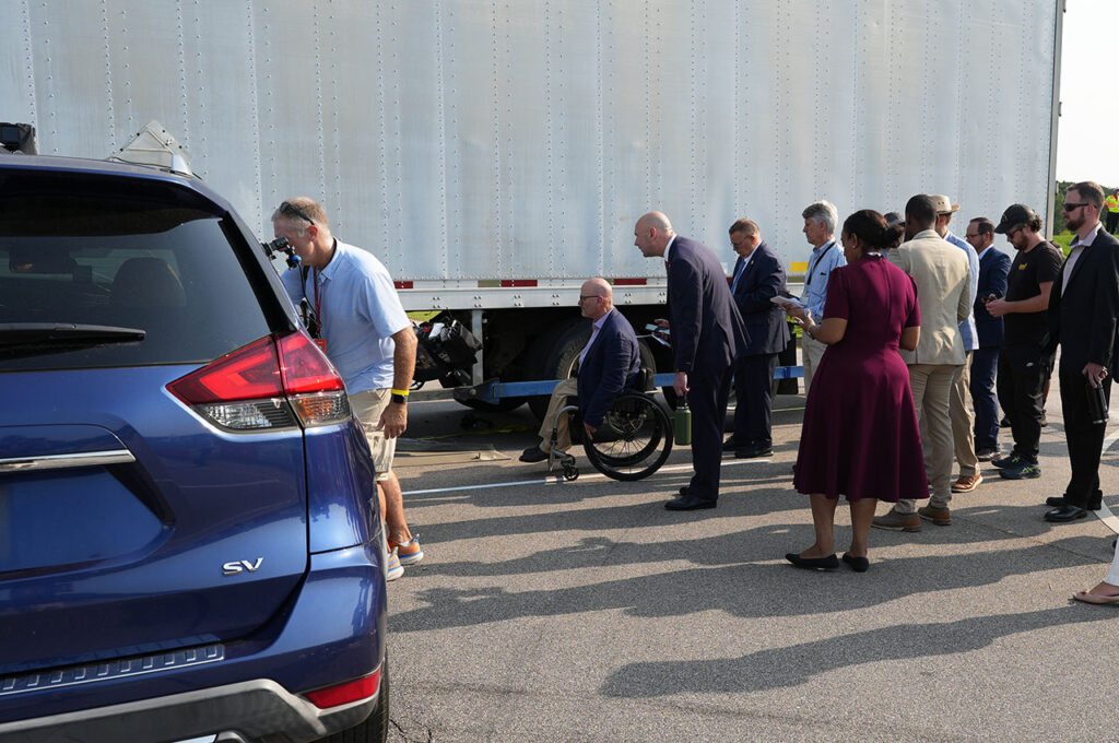 Attendees standing beside vehicles used in the crash-test demonstration
