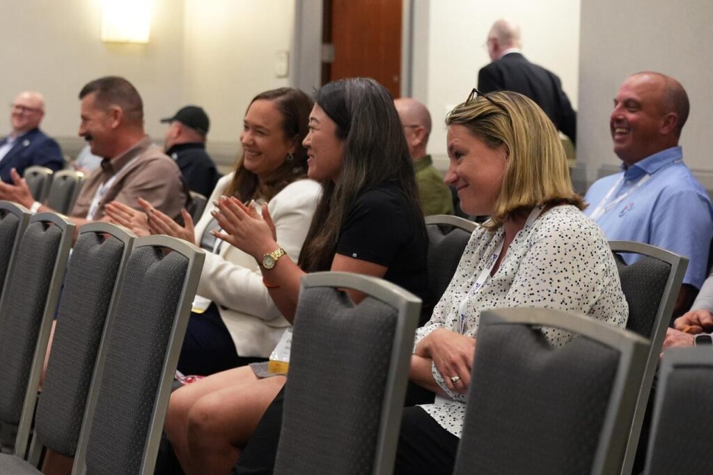 Audience members smiling and applauding at a professional event