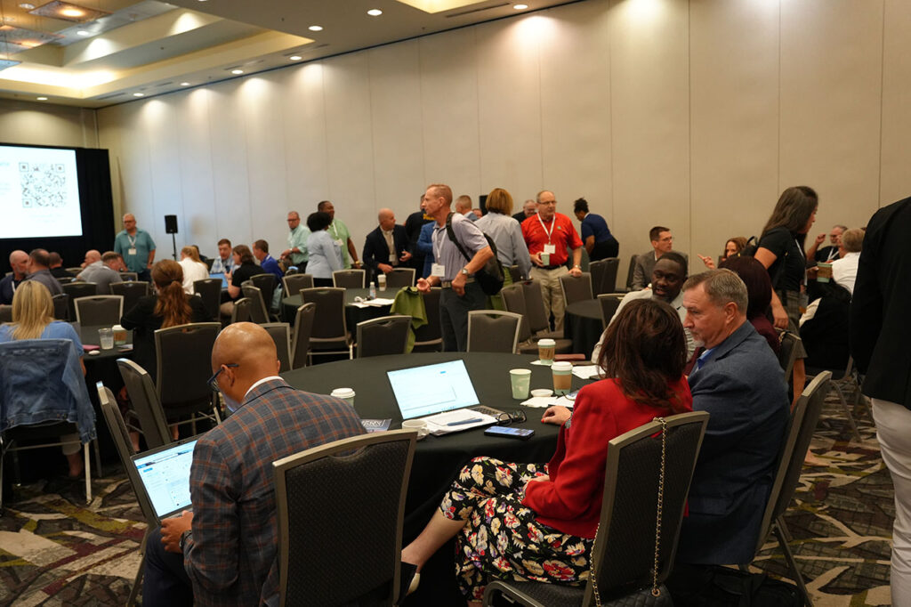 Attendees seated around tables during a Summit general session