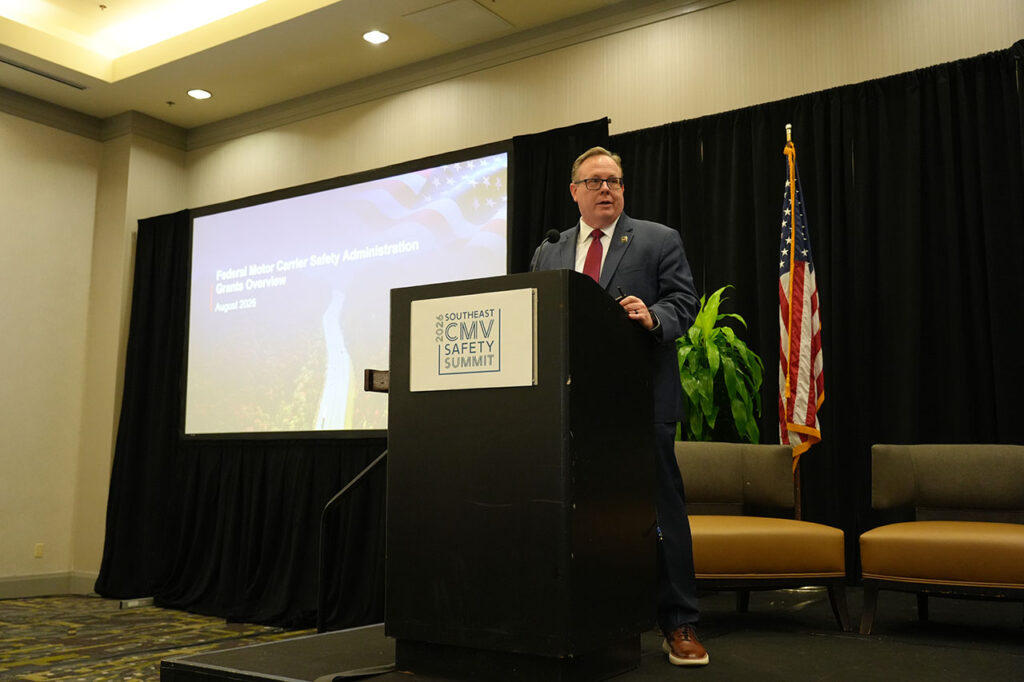 Presenter speaking at a podium in front of the Summit stage