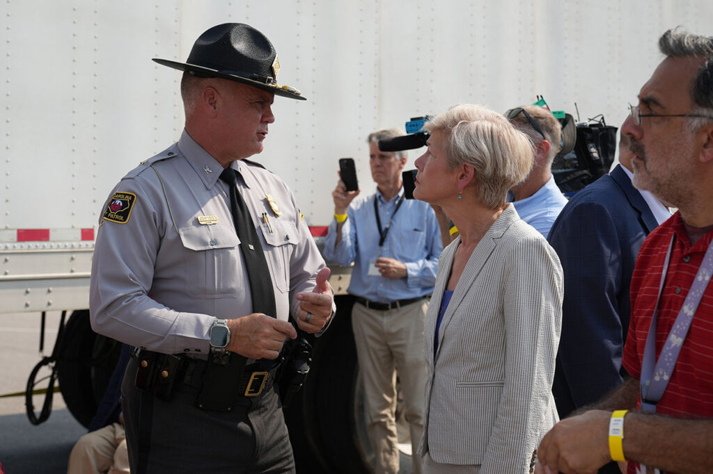 State trooper speaking with an attendee beside the crash-test vehicles