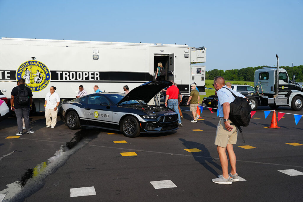 Attendees viewing a passenger vehicle beside a State Highway Patrol trailer